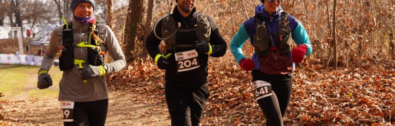 Black Toenail Friday trail Half Marathon and 7.5 Mile race runners with hydration packs on trails at Proud Lake State Rec Area in Commerce Township, MI